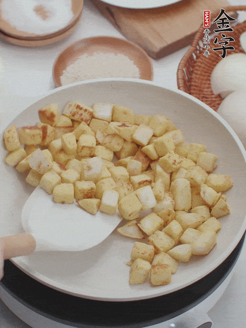 起鍋熱油，倒入饅頭丁，小火煎至蛋液凝固定型再翻面，饅頭丁部煎至金黃時(shí)盛起待用。